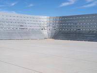 a skateboarder rides down the concrete surface of an empty stadium with seating chairs