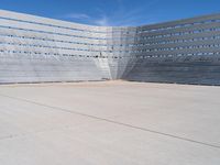 a skateboarder rides down the concrete surface of an empty stadium with seating chairs