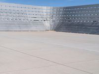 a skateboarder rides down the concrete surface of an empty stadium with seating chairs