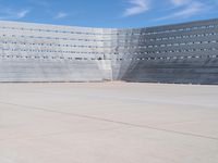 a skateboarder rides down the concrete surface of an empty stadium with seating chairs