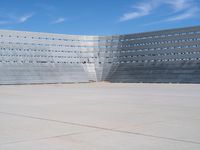 a skateboarder rides down the concrete surface of an empty stadium with seating chairs