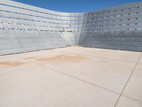 a skateboarder rides down the concrete surface of an empty stadium with seating chairs