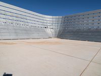 a skateboarder rides down the concrete surface of an empty stadium with seating chairs