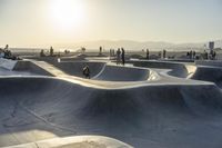 skateboarder riding at a skate park with others nearby, and mountain view in background