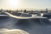 skateboarder riding at a skate park with others nearby, and mountain view in background