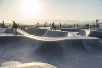 skateboarder riding at a skate park with others nearby, and mountain view in background