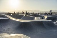 skateboarder riding at a skate park with others nearby, and mountain view in background