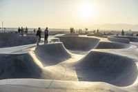 skateboarder riding at a skate park with others nearby, and mountain view in background