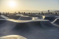 skateboarder riding at a skate park with others nearby, and mountain view in background