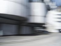 blurred photograph of a skateboarder riding on a city street in front of a building