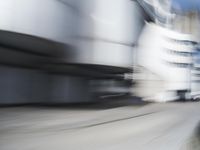 blurred photograph of a skateboarder riding on a city street in front of a building