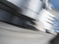 blurred photograph of a skateboarder riding on a city street in front of a building