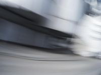 blurred photograph of a skateboarder riding on a city street in front of a building