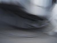 blurred photograph of a skateboarder riding on a city street in front of a building