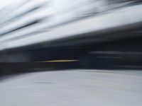 blurred photograph of a skateboarder riding on a city street in front of a building