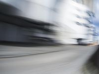 blurred photograph of a skateboarder riding on a city street in front of a building