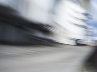 blurred photograph of a skateboarder riding on a city street in front of a building