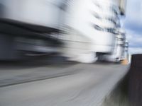 blurred photograph of a skateboarder riding on a city street in front of a building