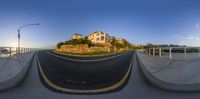 a skateboarder riding on the edge of a ramp next to a home on a steep hill