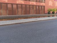 a skateboarder riding the street next to a red building with blinds on it