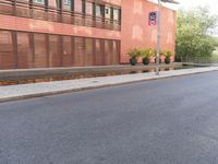 a skateboarder riding the street next to a red building with blinds on it