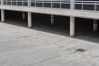 a skateboarder riding underneath an overpass in the city, outside a building