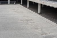 a skateboarder riding underneath an overpass in the city, outside a building