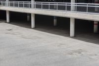 a skateboarder riding underneath an overpass in the city, outside a building