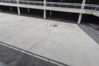 a skateboarder riding underneath an overpass in the city, outside a building