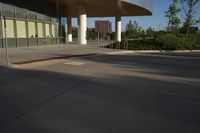 a skateboarder rides in a parking lot next to buildings with tall windows,