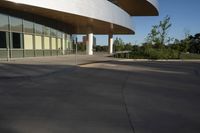 a skateboarder rides in a parking lot next to buildings with tall windows,