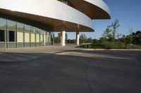 a skateboarder rides in a parking lot next to buildings with tall windows,