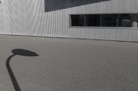 the shadow of a person riding on a skateboard in front of a building with a large window