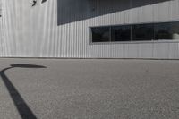 the shadow of a person riding on a skateboard in front of a building with a large window