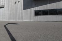 the shadow of a person riding on a skateboard in front of a building with a large window