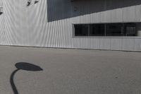 the shadow of a person riding on a skateboard in front of a building with a large window