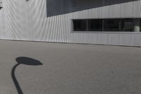 the shadow of a person riding on a skateboard in front of a building with a large window