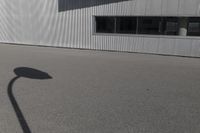 the shadow of a person riding on a skateboard in front of a building with a large window