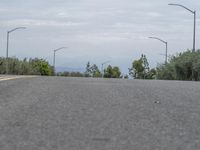 a lone skateboarder sits on the side of a road overlooking mountains and trees