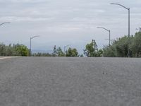 a lone skateboarder sits on the side of a road overlooking mountains and trees