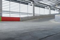 a skateboarder skating on a cement surface under a garage with bright lights above