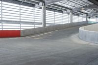 a skateboarder skating on a cement surface under a garage with bright lights above