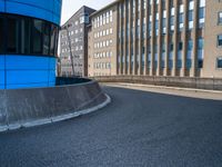 skateboarder skating near the side of a building in an alley with big windows