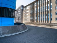 skateboarder skating near the side of a building in an alley with big windows