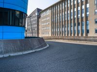 skateboarder skating near the side of a building in an alley with big windows