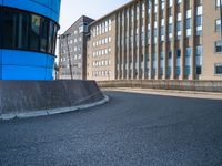 skateboarder skating near the side of a building in an alley with big windows