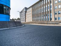 skateboarder skating near the side of a building in an alley with big windows