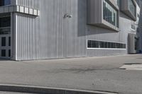 a skateboarder on the sidewalk in front of a tall building that is open