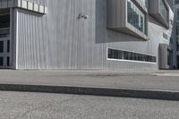 a skateboarder on the sidewalk in front of a tall building that is open