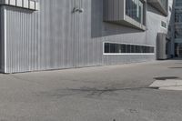 a skateboarder on the sidewalk in front of a tall building that is open